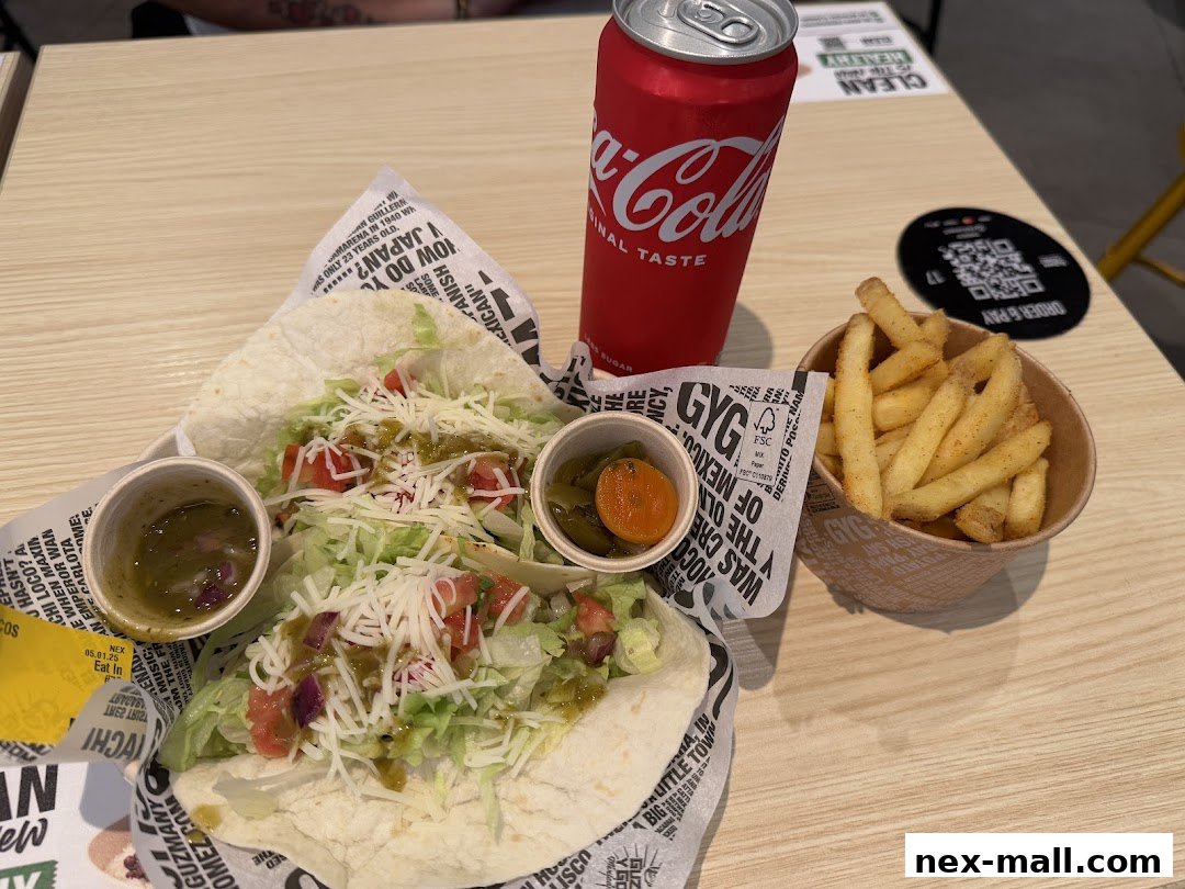 A meal from Guzman y Gomez featuring two tacos, fries, a drink, and dipping sauces.