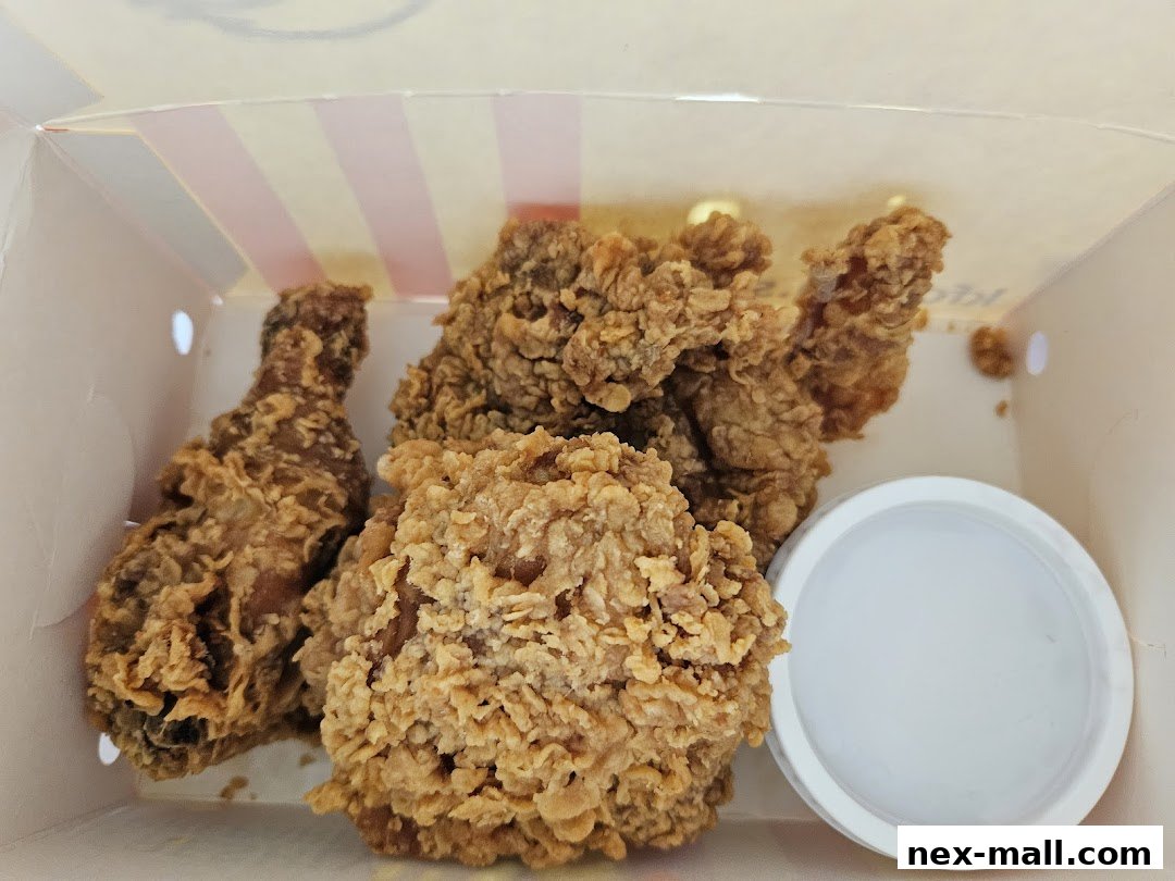 A box of crispy fried chicken pieces with a side of dipping sauce.