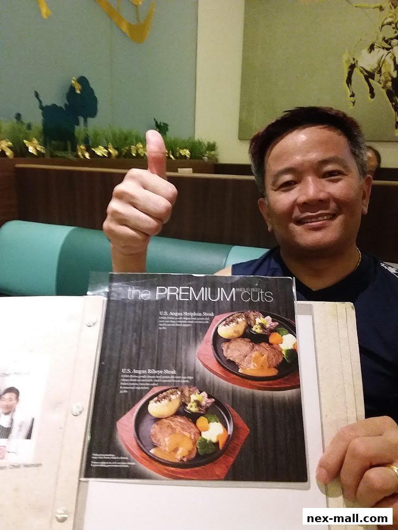 A man gives a thumbs up while holding a menu featuring premium steak cuts.