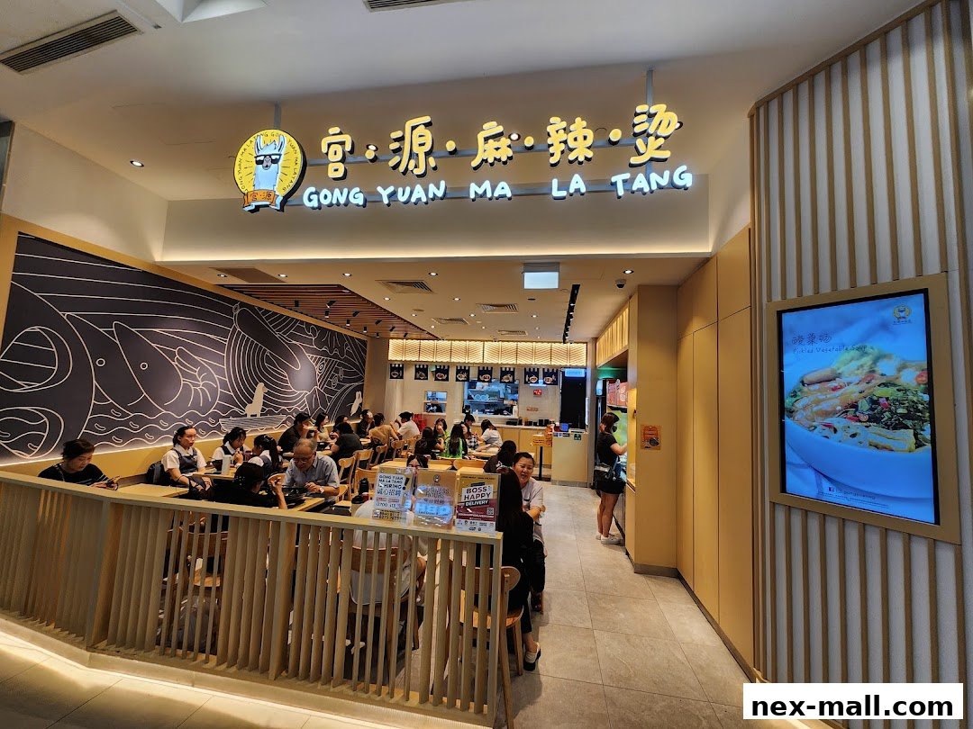 Interior view of Gong Yuan Ma La Tang restaurant with diners and a digital menu display.
