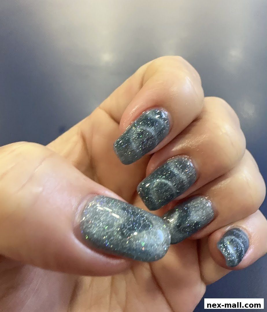 Close-up of a hand with stylish grey cat-eye gel nails with glitter.