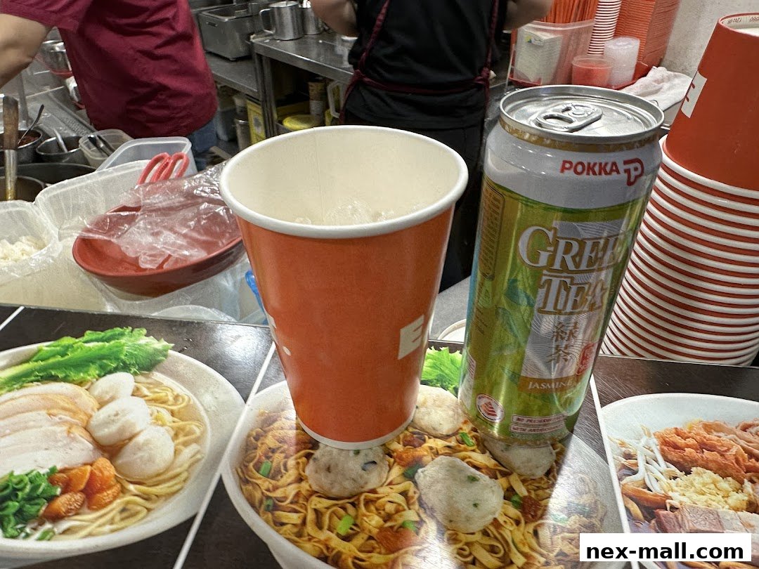 A close-up of food images with a drink and stacked cups at a food stall.