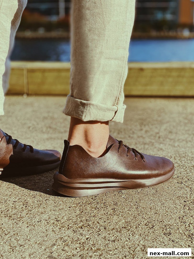 Close-up of a person wearing stylish brown leather sneakers with rolled-up pants.