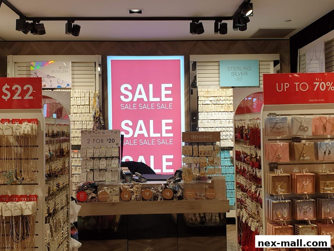 A brightly lit jewelry store with 'SALE' signs and displays of necklaces and earrings.