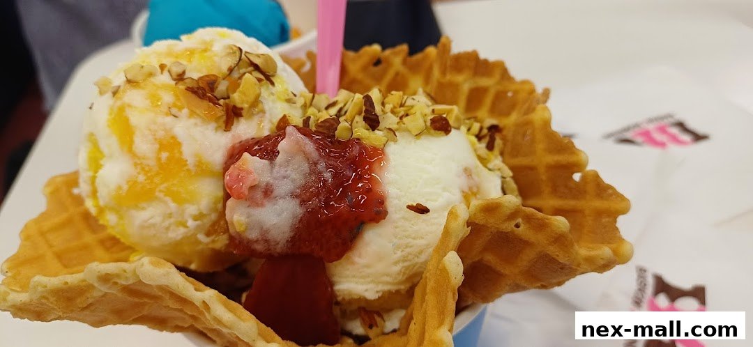 A close-up of a waffle cone filled with ice cream, topped with nuts and strawberry sauce.