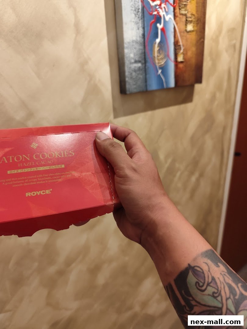 A hand holds a red box of Royce Hazel Cacao Baton Cookies.