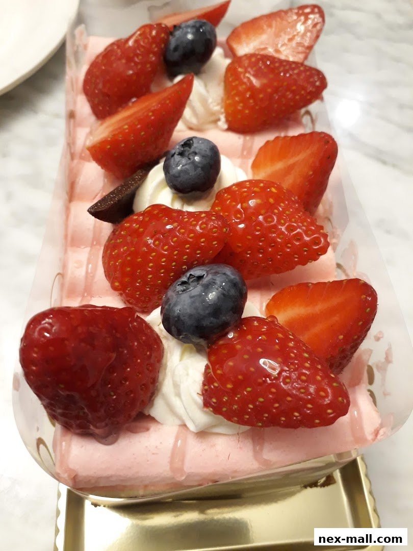 A close-up of a strawberry and blueberry cake with whipped cream and chocolate.