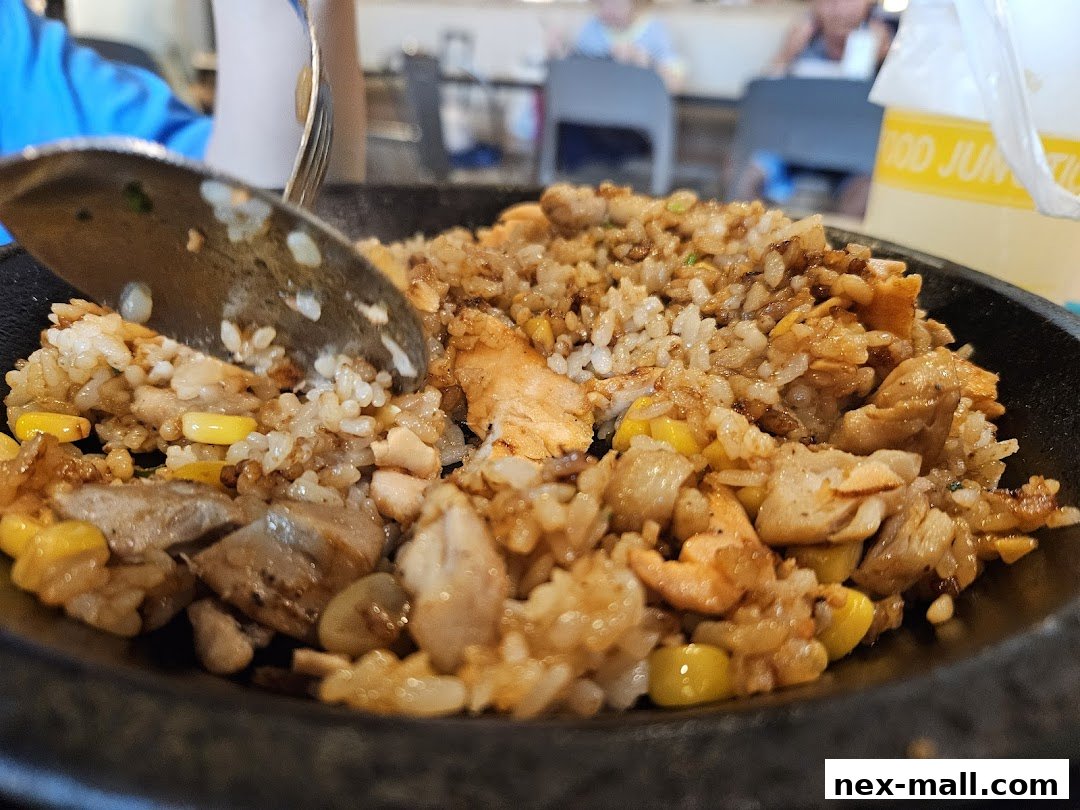 A close-up shot of a sizzling hot plate of chicken and corn fried rice.