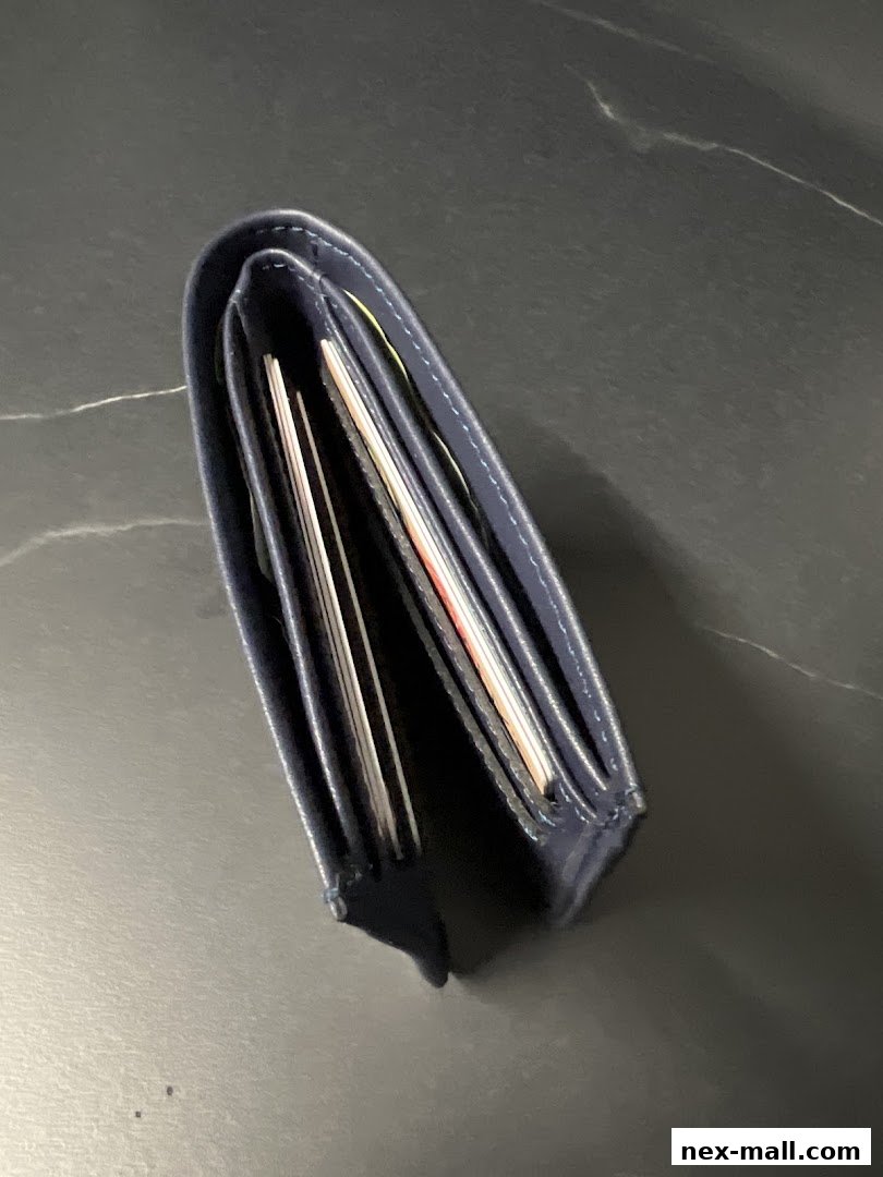 A dark blue leather wallet filled with cards and cash, resting on a dark surface.