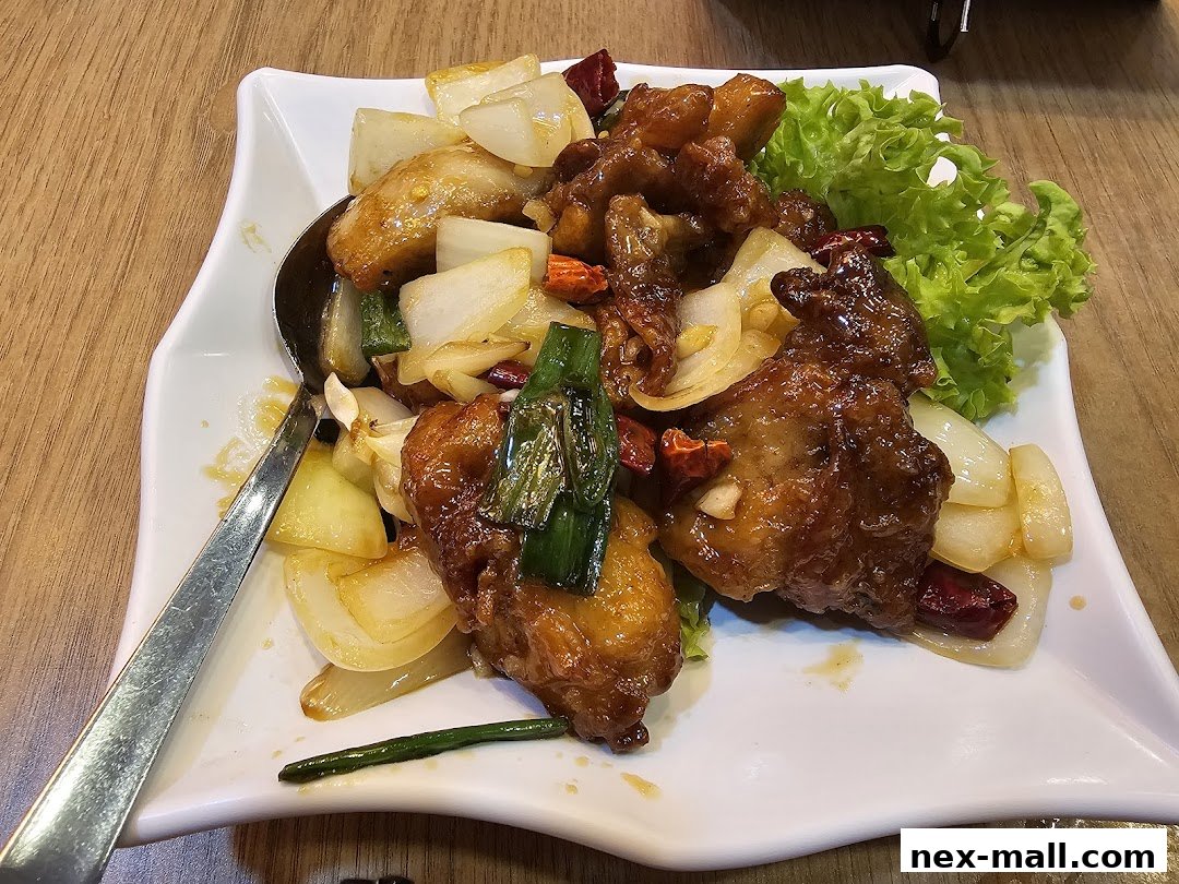 A plate of savory stir-fried chicken with onions, chili, and lettuce.