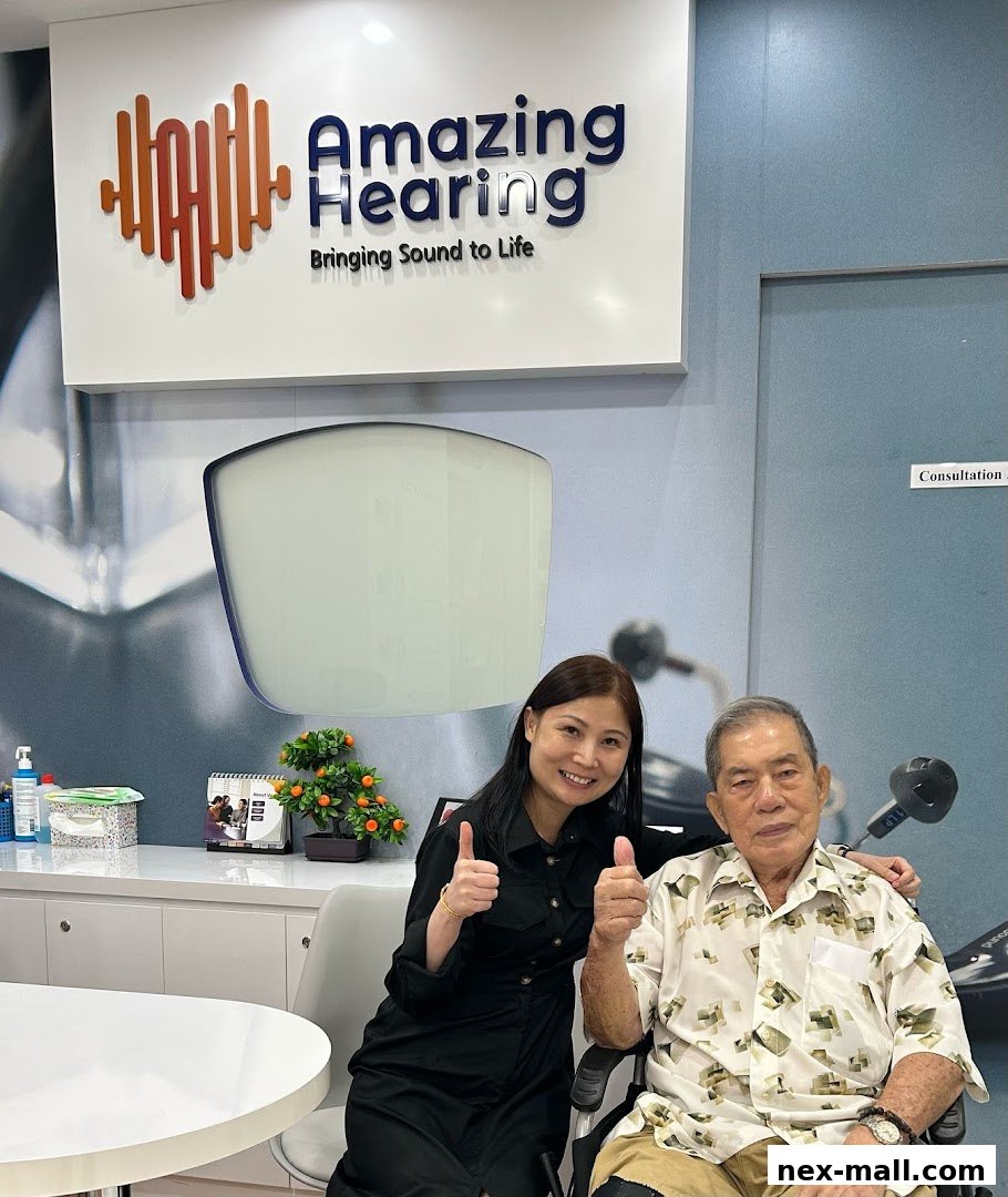 A woman and an elderly man give thumbs up in front of the Amazing Hearing logo.