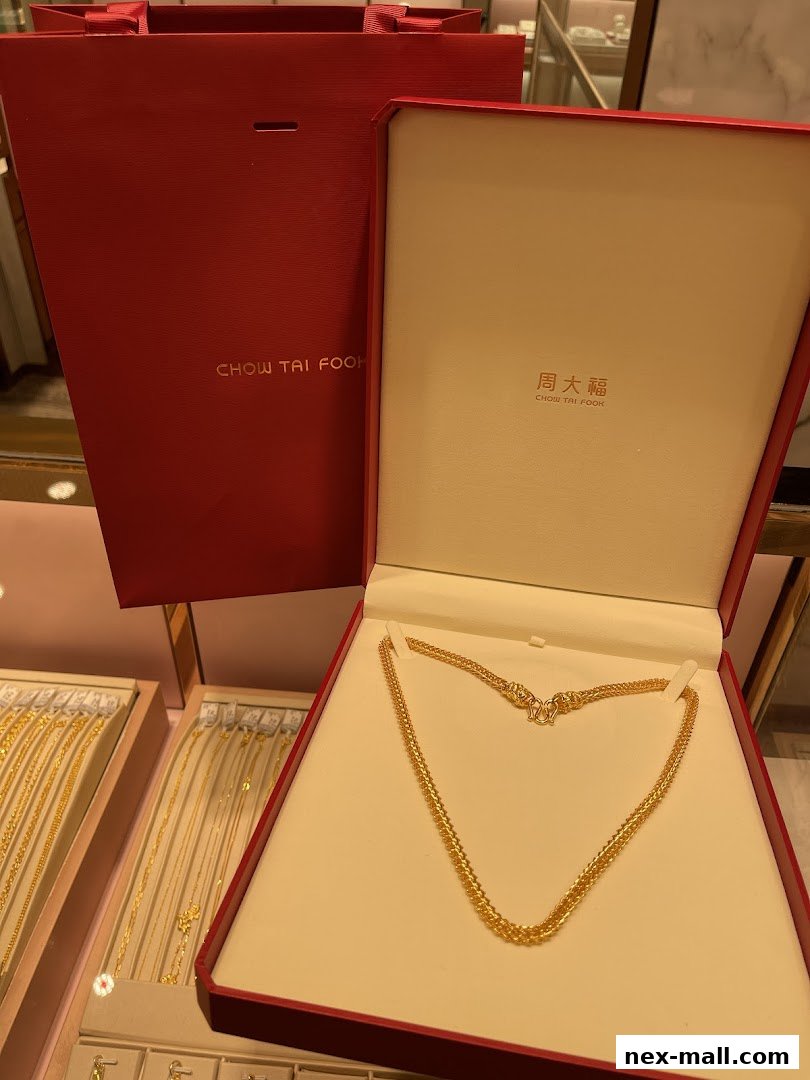 A gold necklace displayed in a red Chow Tai Fook jewellery box with a shopping bag.