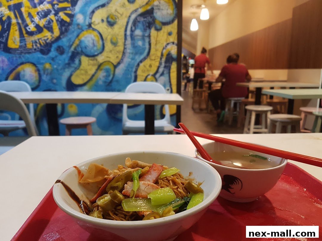 A close-up of a bowl of noodles and soup with chopsticks, in a cafe with colorful wall art.