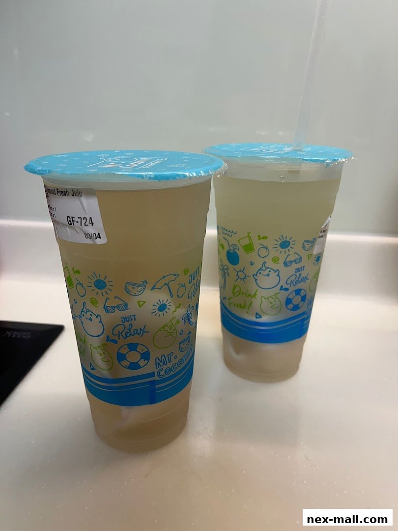 Two cups of Mr. Coconut Fresh Juice with straws on a countertop.