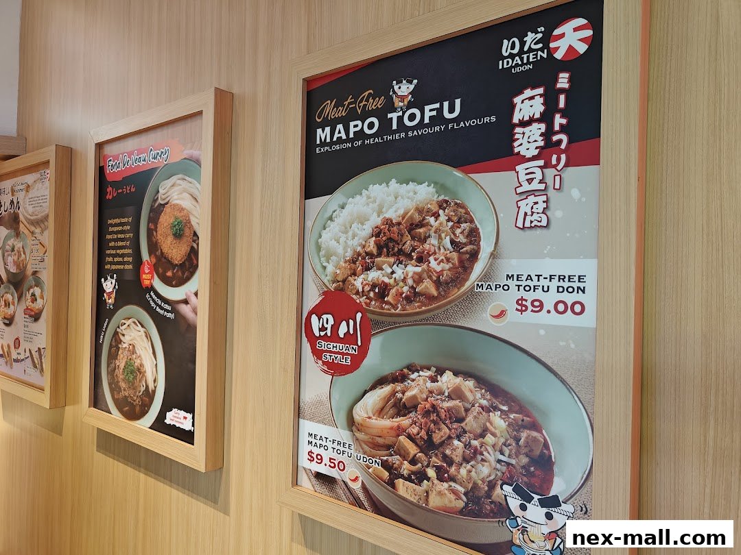 A display of menu items from Idaten Udon, featuring curry udon and mapo tofu dishes.