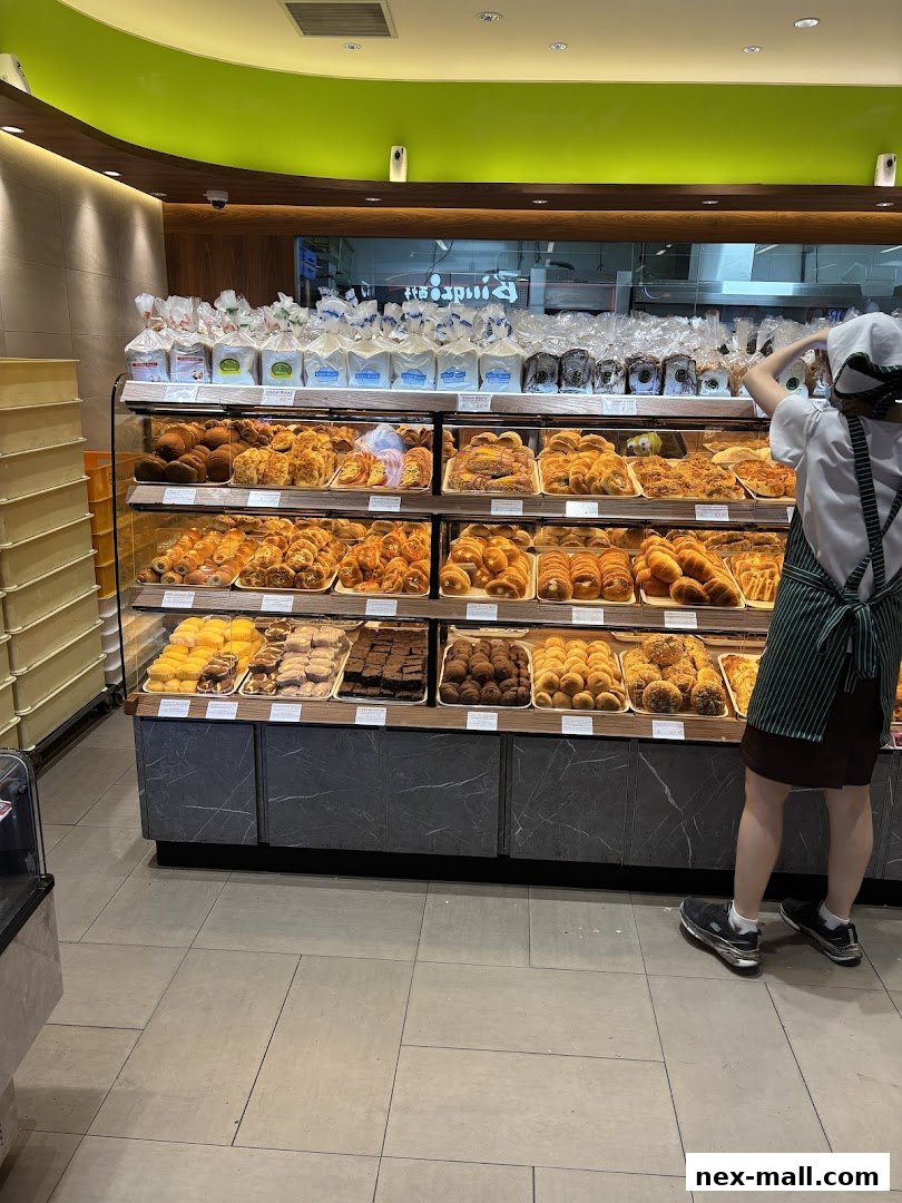 A baker arranging pastries and bread in a display case at Four Leaves bakery.