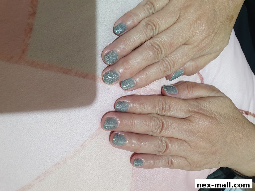 Close-up of hands with neatly manicured nails painted in a shimmering grey polish.
