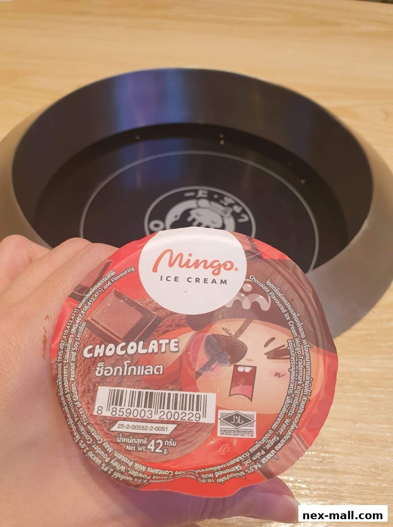A hand holds a cup of Mingo Chocolate Ice Cream with a cartoon pirate character.