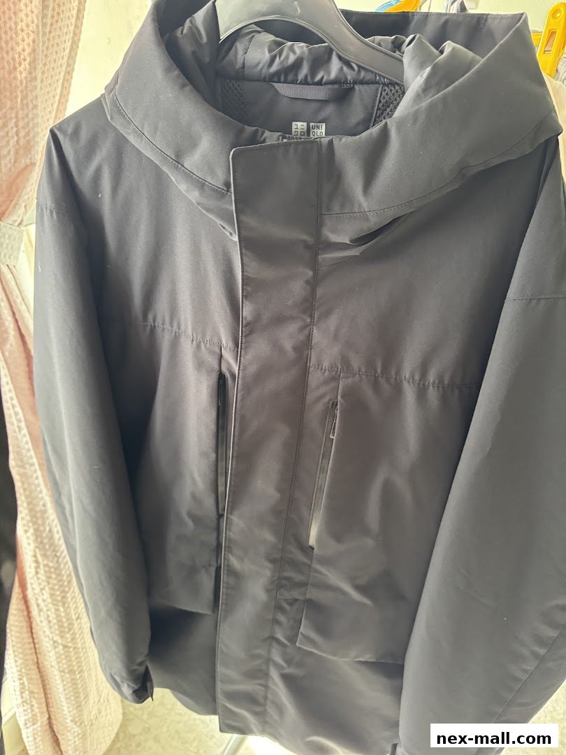 A close-up view of a black Uniqlo jacket with a high collar and zippered pockets.