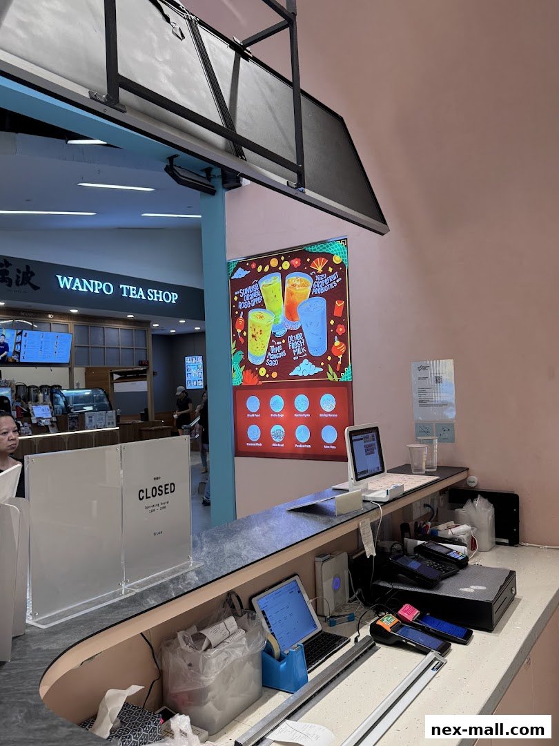 A counter at Fruce NEX with a digital menu displaying drinks and payment terminals.