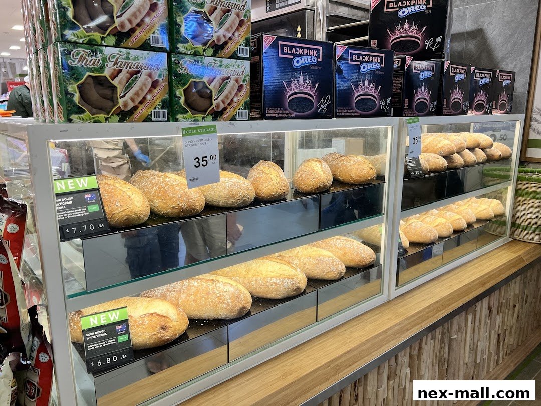 A display case filled with various types of bread, with boxes of Blackpink Oreo and Thai Tamarind products above.