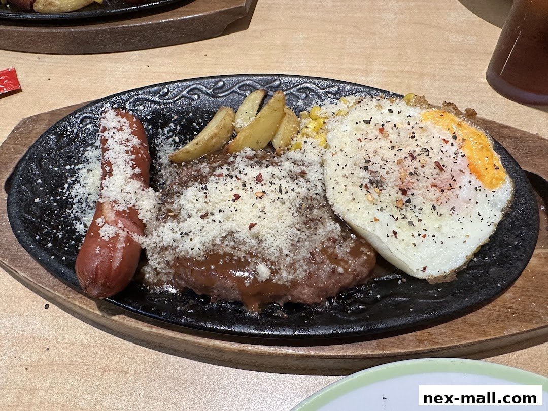 A sizzling platter with a sausage, hamburger steak, fried egg, and fries.