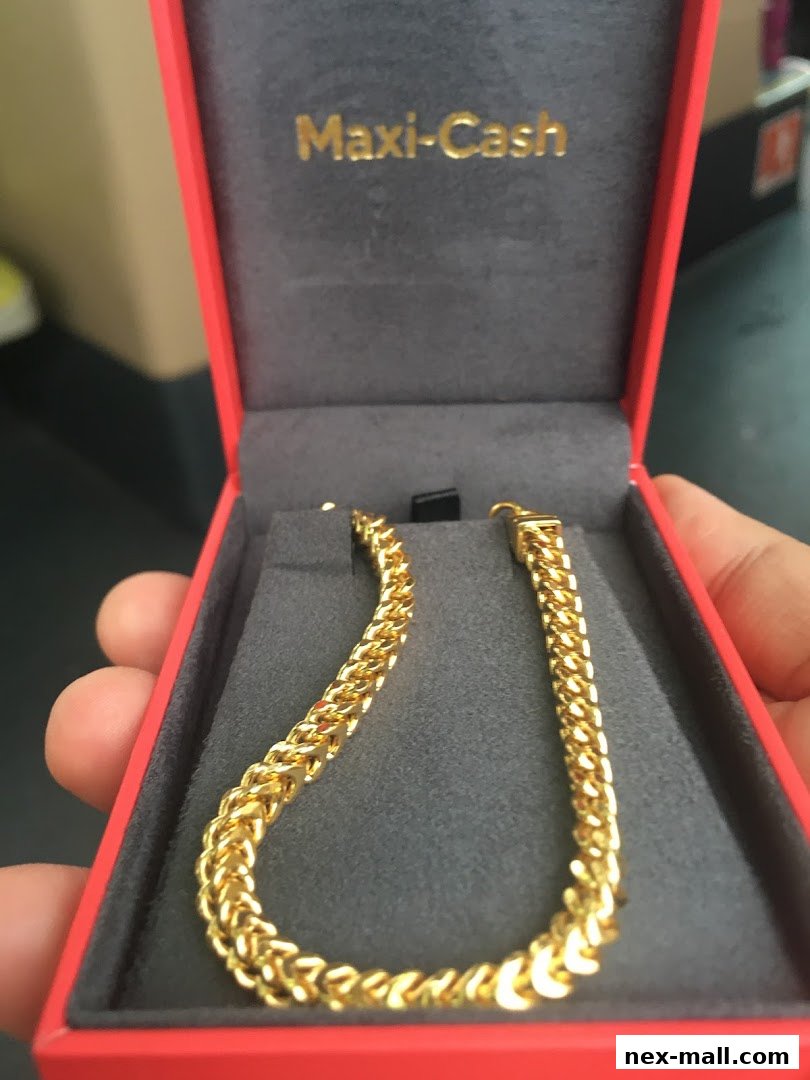 A hand holds a gold chain presented in a red jewelry box with Maxi-Cash branding.