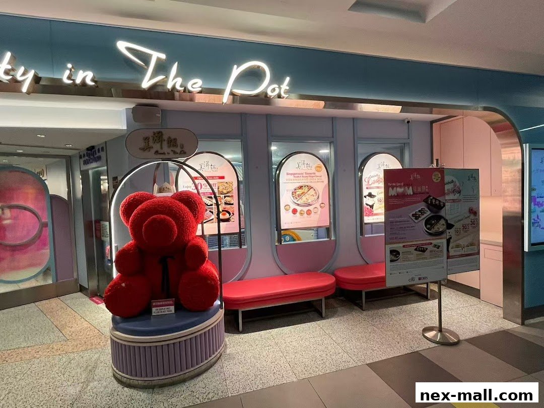 The entrance of Beauty in The Pot at NEX, featuring a large red teddy bear and promotional posters.