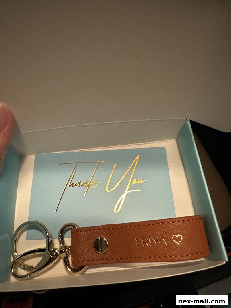 A personalized brown leather keychain with a gold heart and name, presented in a gift box.