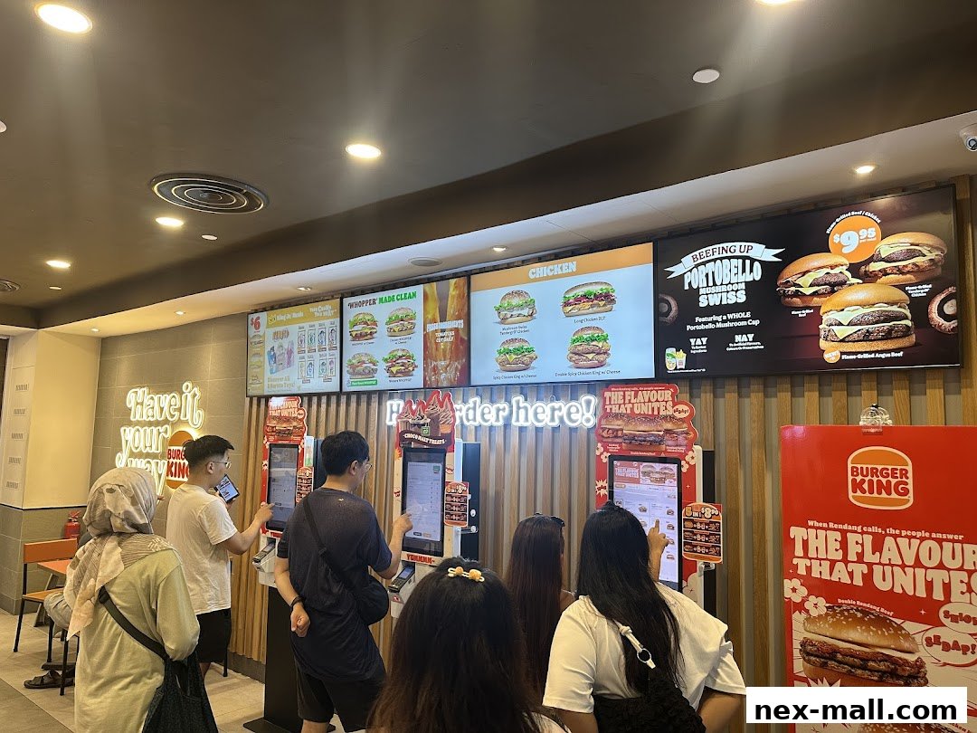 Customers ordering at self-service kiosks in a Burger King restaurant with digital menu boards.
