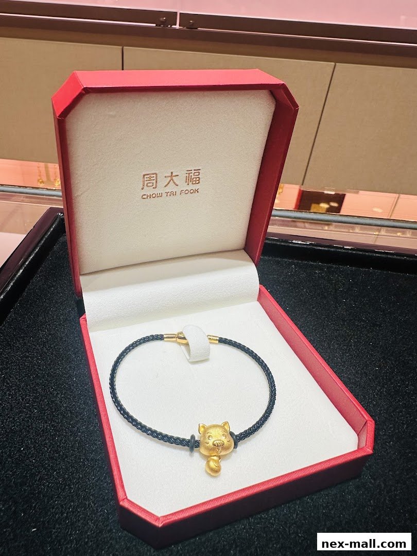 A gold bracelet with a pig charm in a red jewelry box.