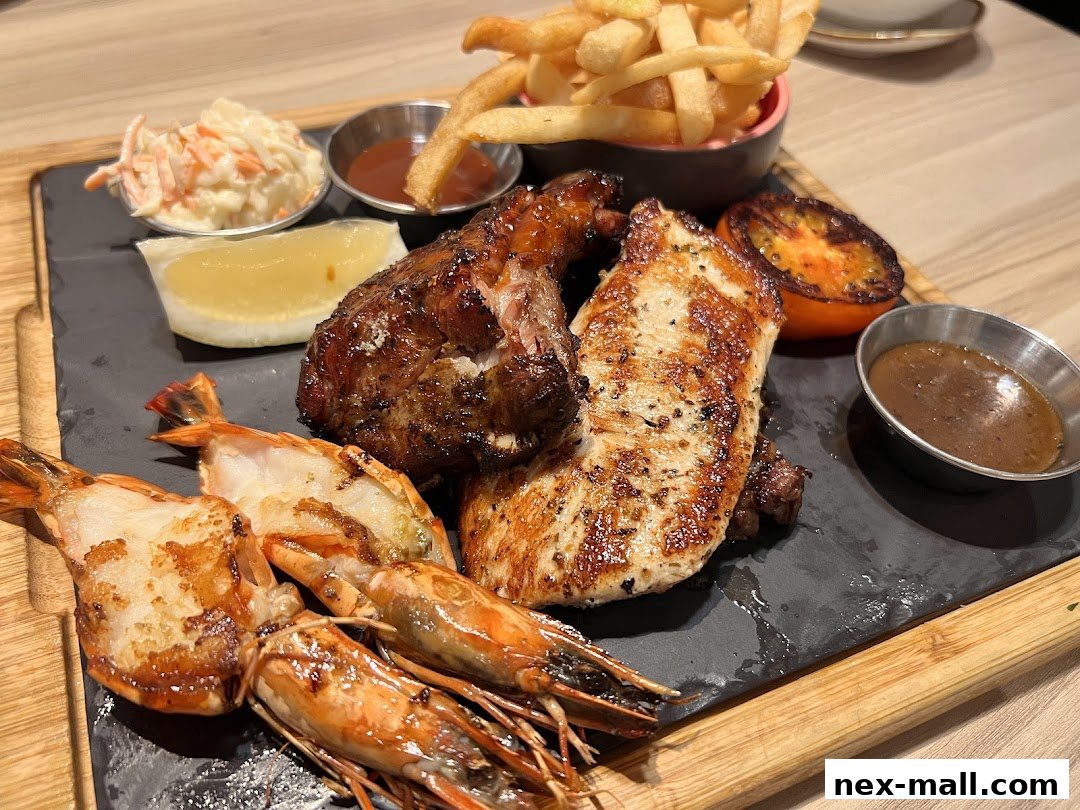 A platter of grilled meats, prawns, fries, coleslaw, and sauces on a slate board.