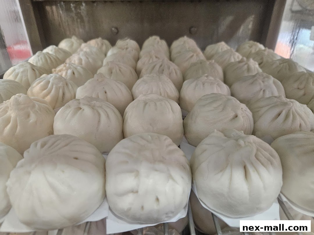 A close-up view of many freshly steamed bao buns arranged in rows.
