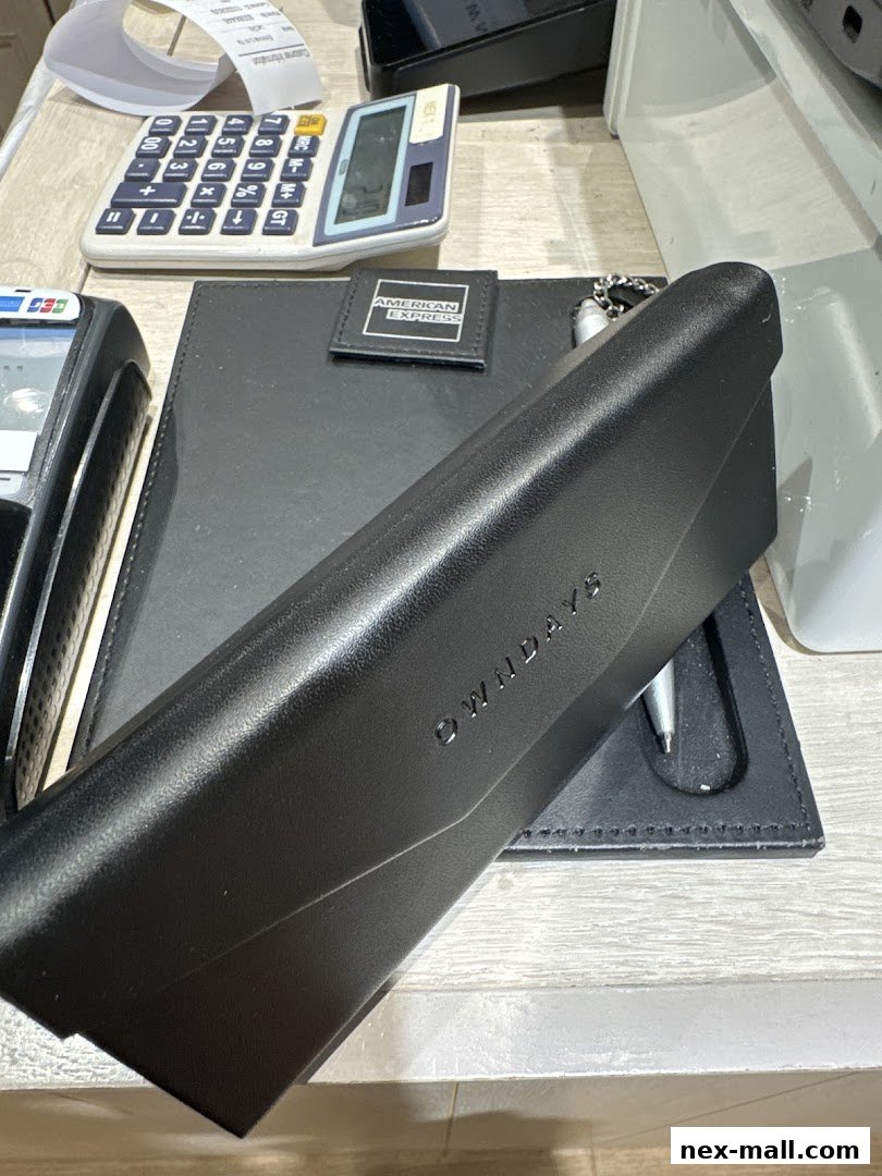 A black OWNDAYS glasses case rests on a black folder with an American Express logo.