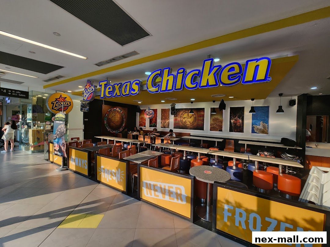 The exterior of Texas Chicken NEX restaurant with seating and prominent signage.