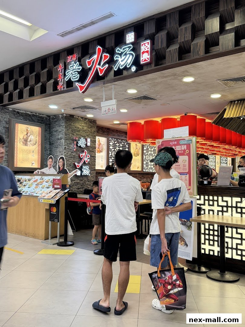 People queuing at the entrance of a restaurant with a prominent sign and menu display.