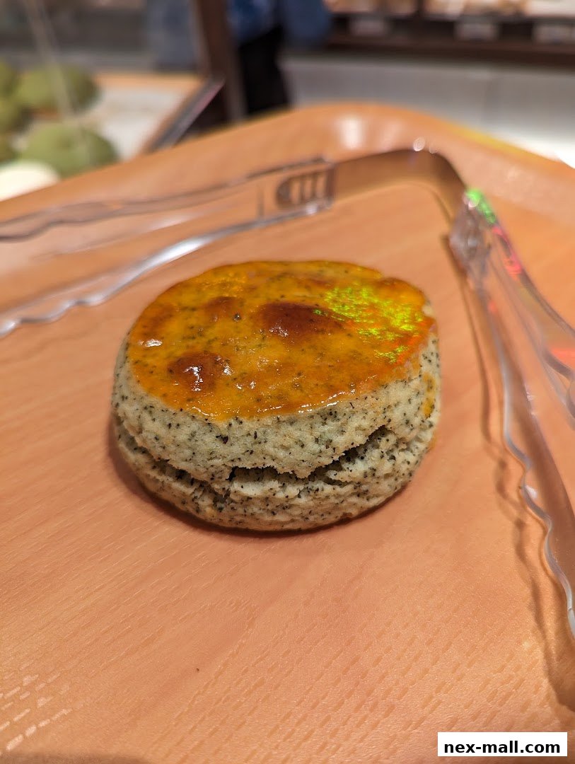 A close-up of a Japanese scone with a glossy topping and visible tea leaves.