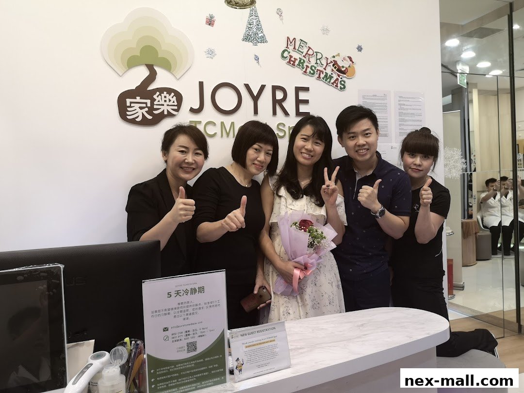 A group of five people, likely staff and a customer, pose for a photo at the reception of Joyre TCMedi Spa.