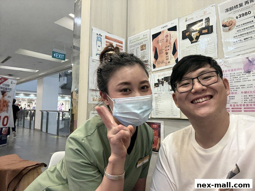 A smiling woman in a mask and a man pose for a selfie in front of promotional posters.