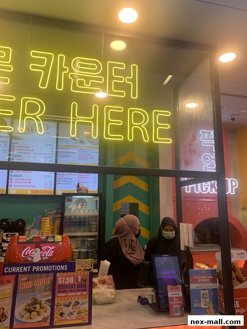 A view of the counter at JINJJA Chicken with staff and menu boards visible.