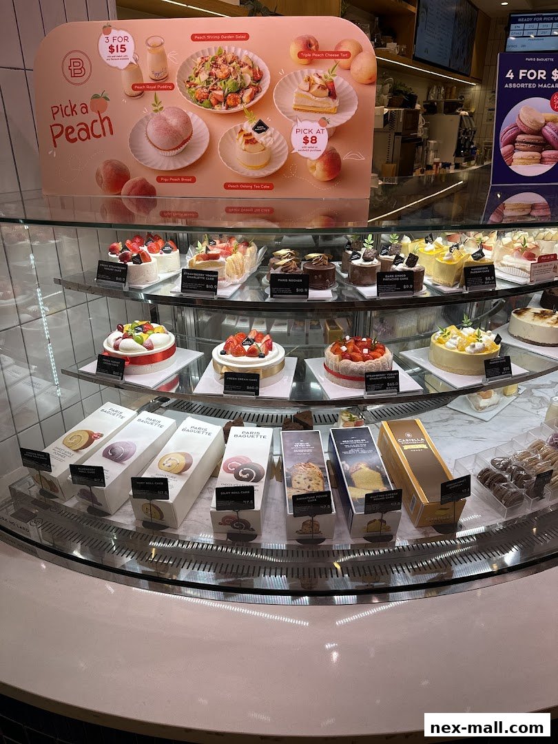 A display case filled with various cakes, pastries, and desserts, with a promotional sign for peach-themed items.