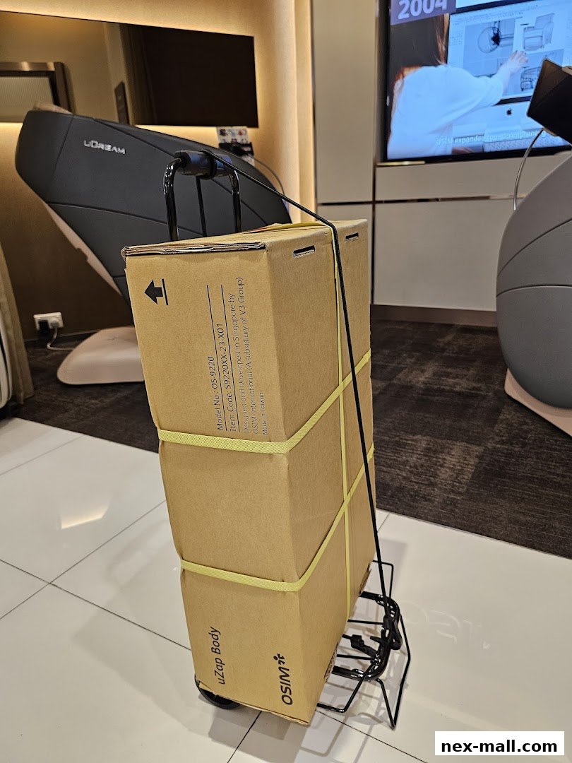 OSIM branded boxes are stacked on a trolley in front of a massage chair.