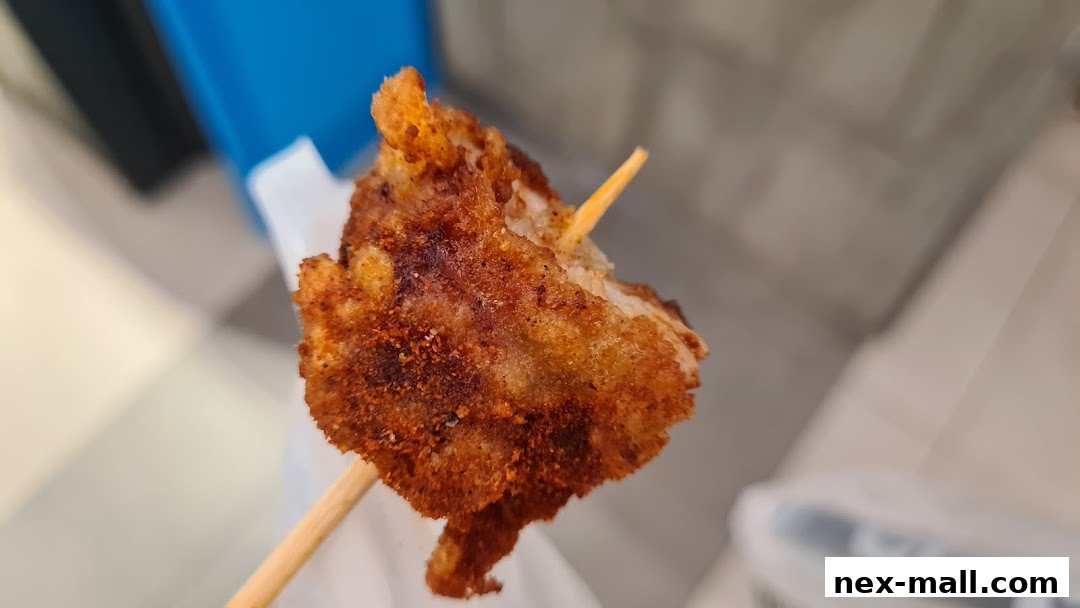 A close-up shot of a piece of fried chicken on a skewer, seasoned with spices.