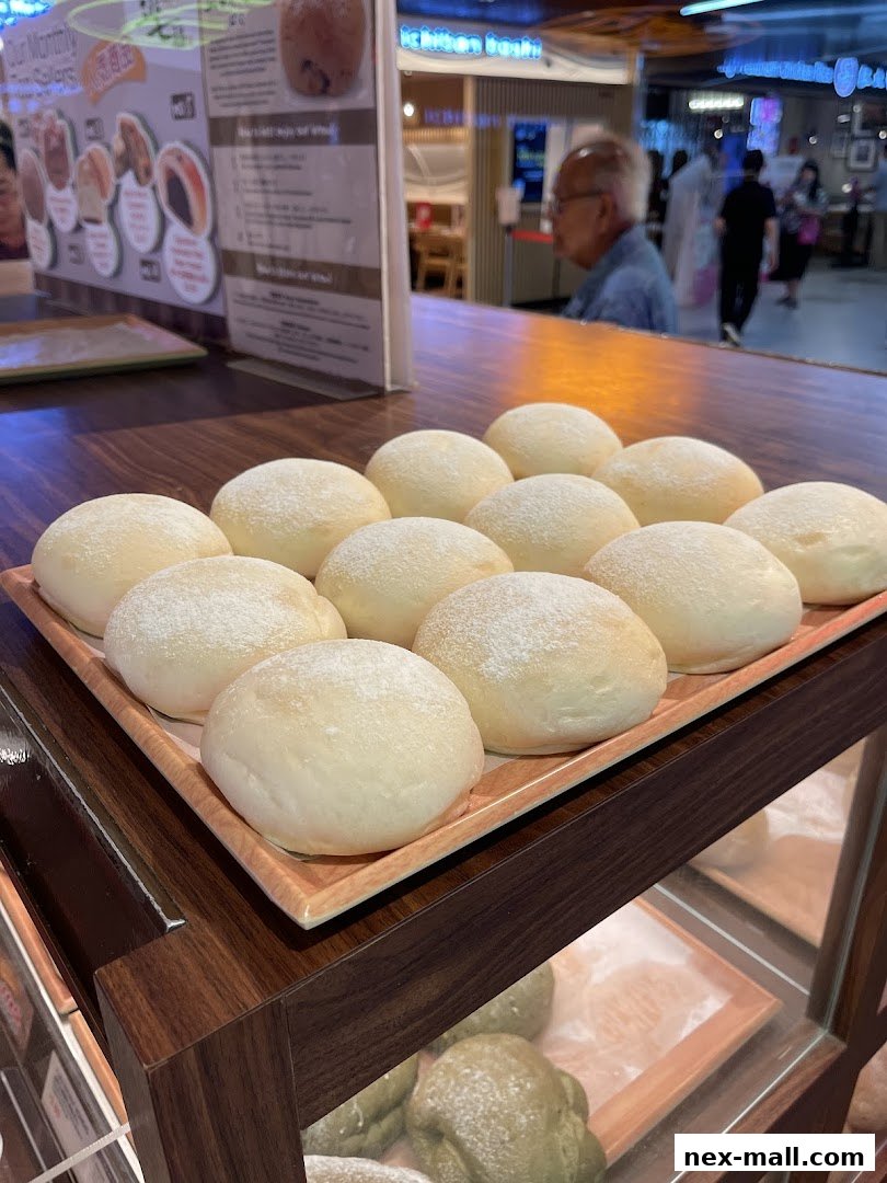 A tray of freshly baked, powdered Japanese sweet buns is displayed in a bakery.