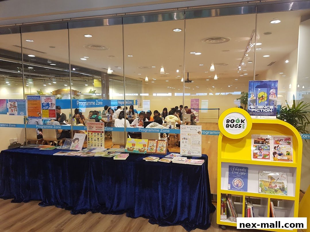 A library's 'Programme Zone' with books displayed and people seated at tables.