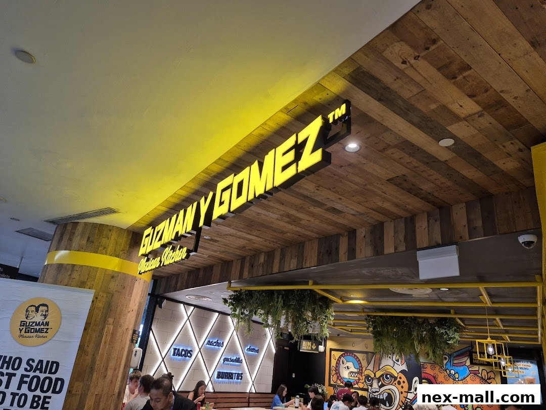 The interior of a Guzman y Gomez restaurant with a prominent sign and colorful murals.