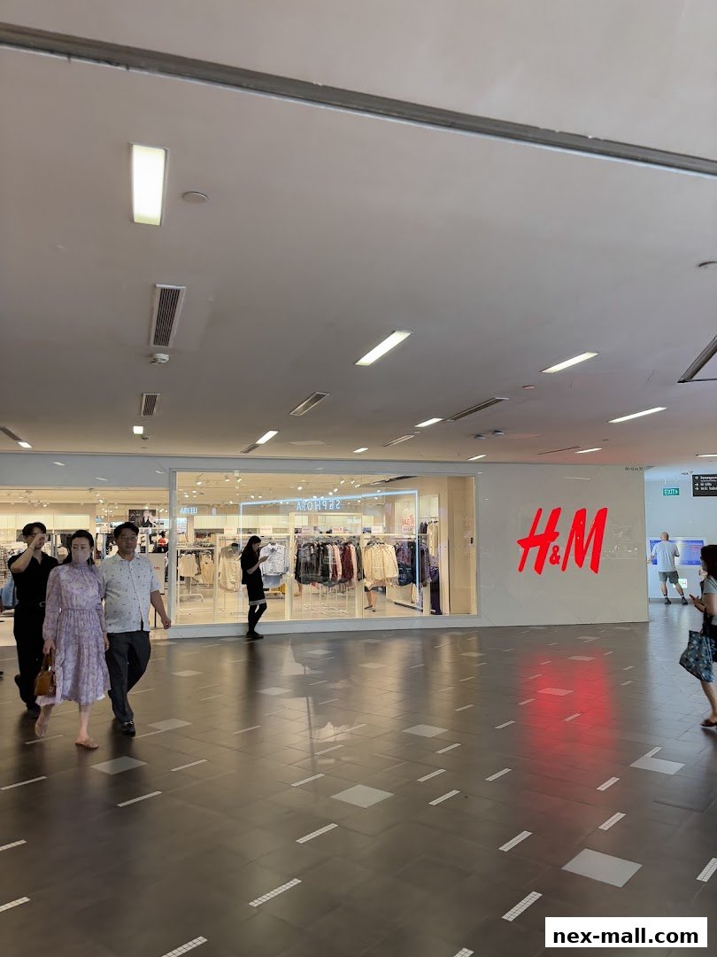 The H&M store entrance with clothing displayed inside and people walking by.