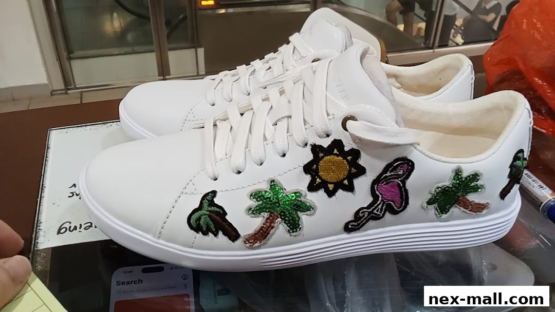 A pair of white sneakers adorned with colorful embroidered patches of palm trees, a flamingo, and a sun.