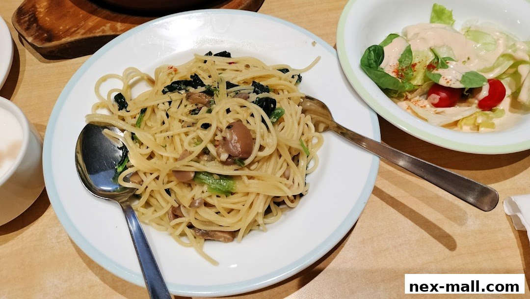 A plate of spaghetti with mushrooms and spinach, served with a side salad.