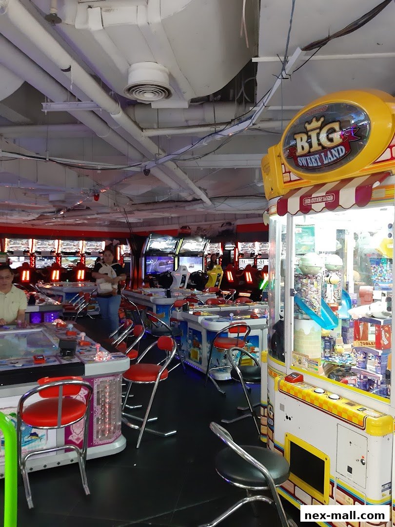 Interior of an arcade with various game machines and seating.